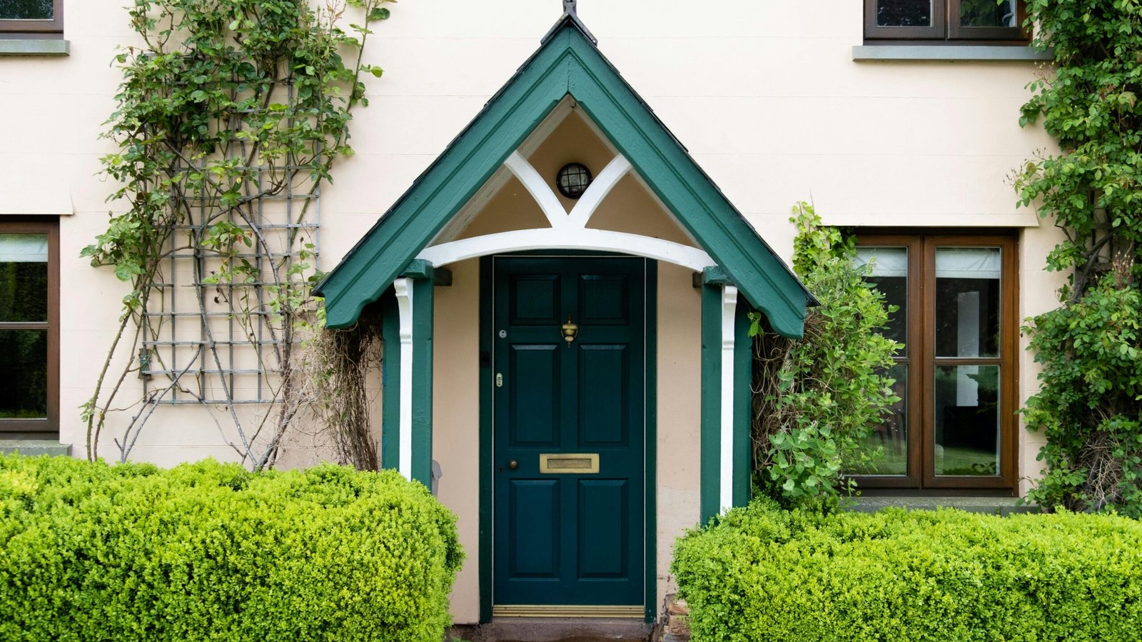 Quaint cottage entrance with green door and ivy in Hereford, England.