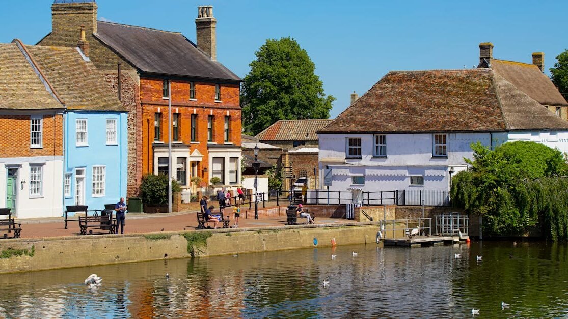 Historic English village with colorful houses reflecting on a serene river.